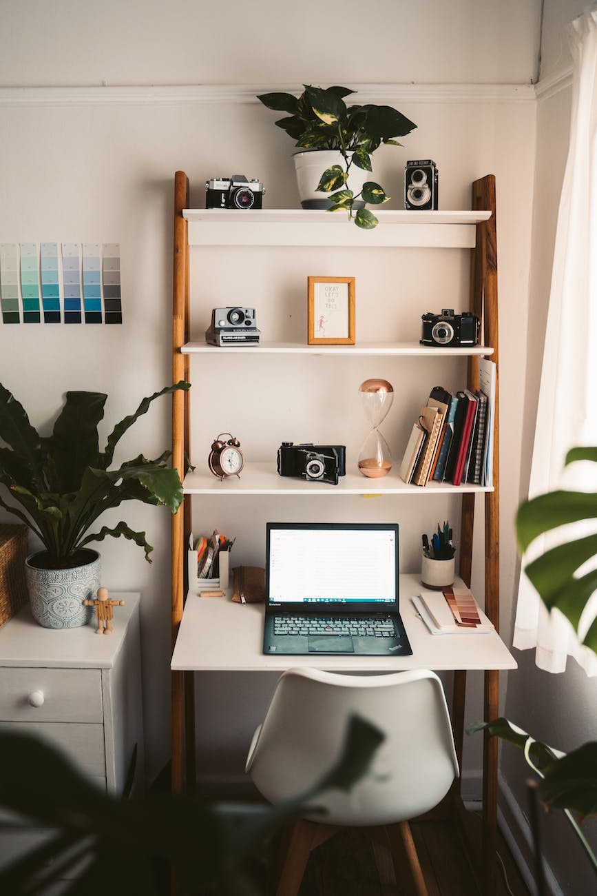 close up shot of a chair near a desk with decorations. ladder shelf turned into small home office