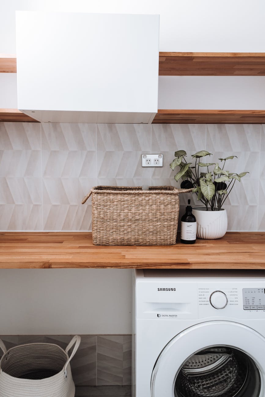 washing machine under wooden table with plant and wicker basket