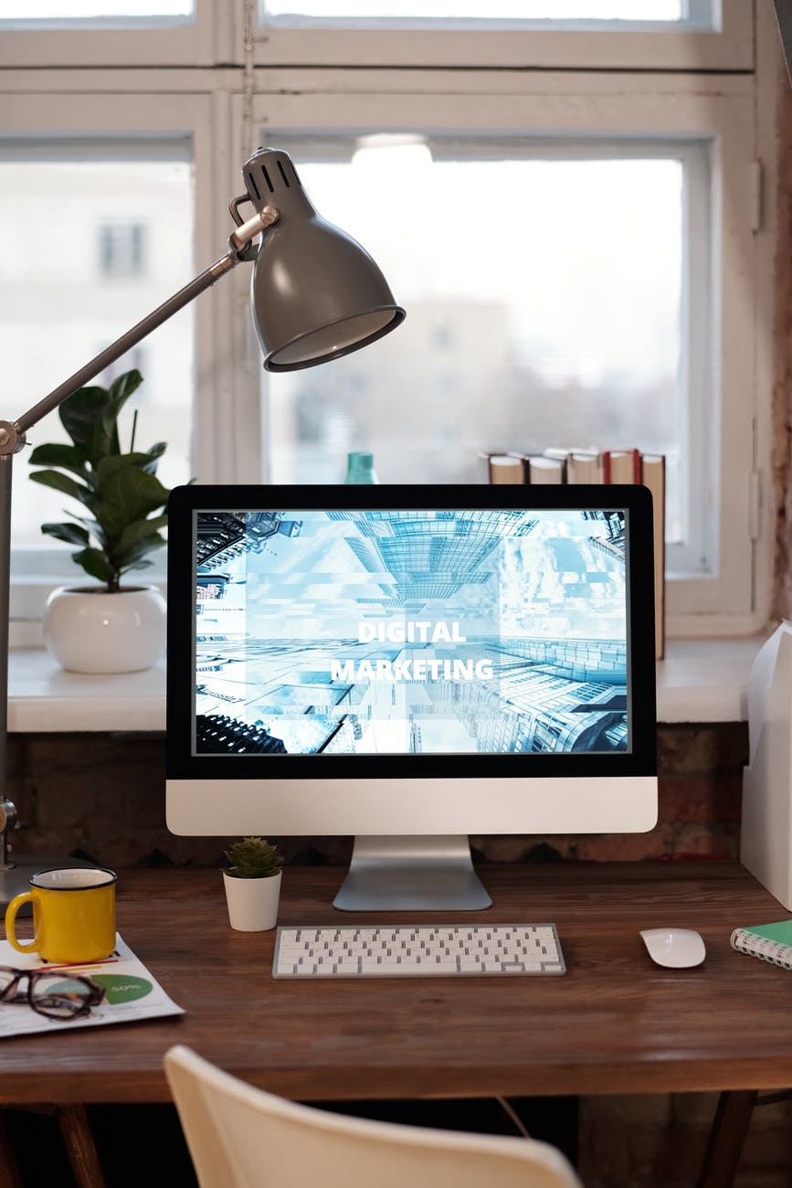 silver imac on brown wooden table near windowsill